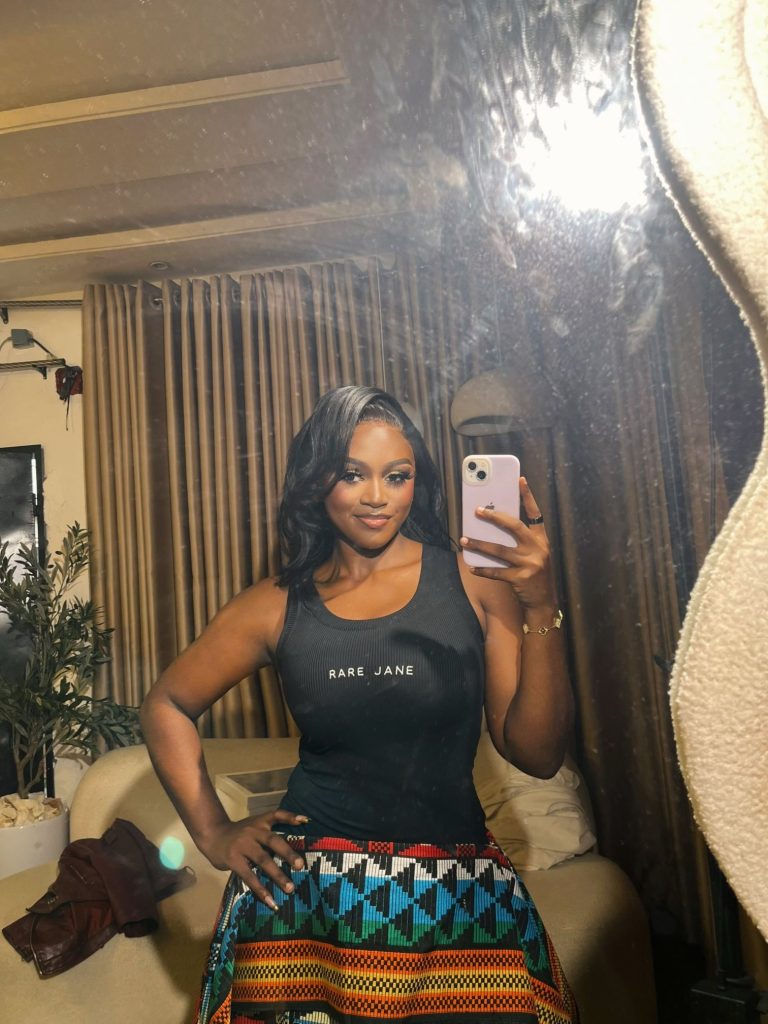 Customer wearing the Rare Jane Essence Tank Top in black with a kente print skirt